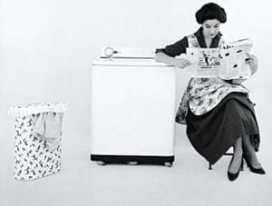 Donna legge il giornale mentre la lavatrice lavora