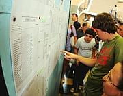Ragazzi guardano gli scrutini appendi al muro del liceo