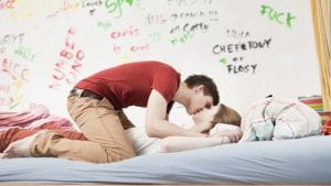 Due giovani che si baciano su un letto.