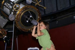 Un bambino guarda in un enorme telescopio.