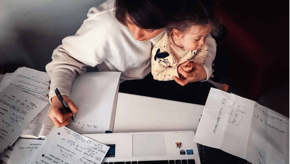 A woman writing holding a child in heh arms