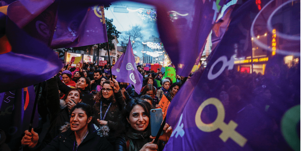 Donne con bandiere viola a una mostra per la giornata internazionale della donna. 