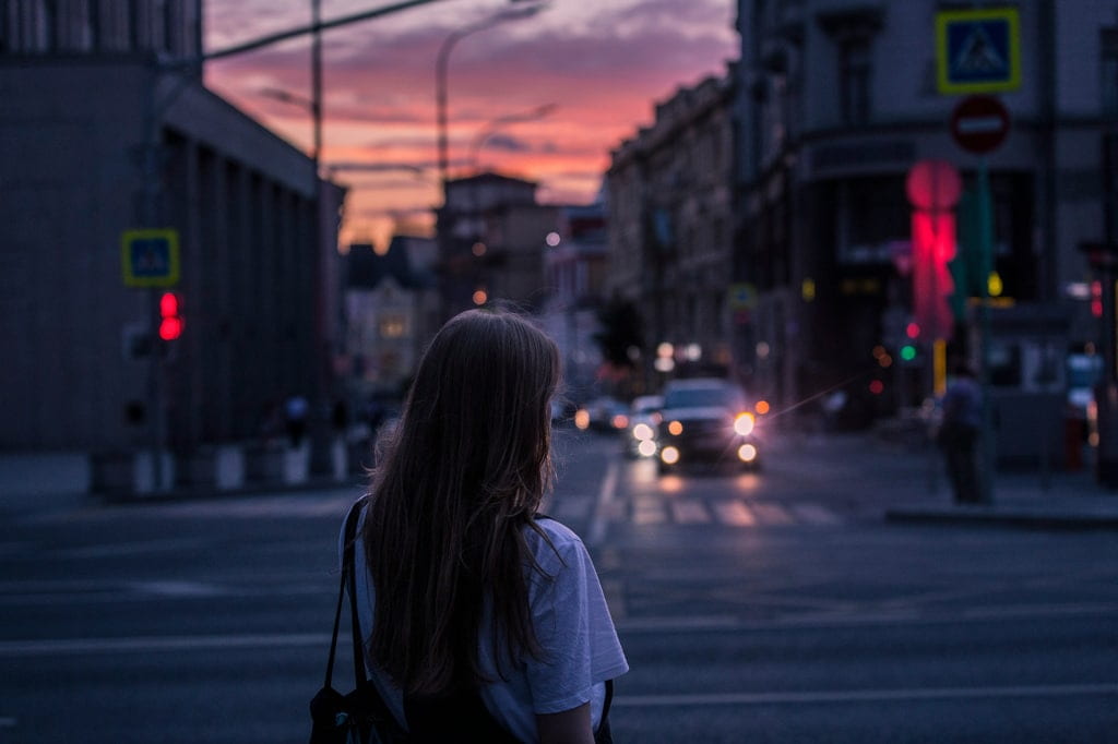 Donna di spalle e sullo sfondo una strada di notte